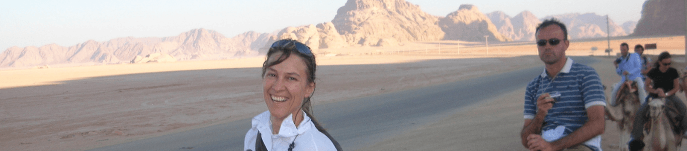 Woman in a desert riding on a camel with a group of friends